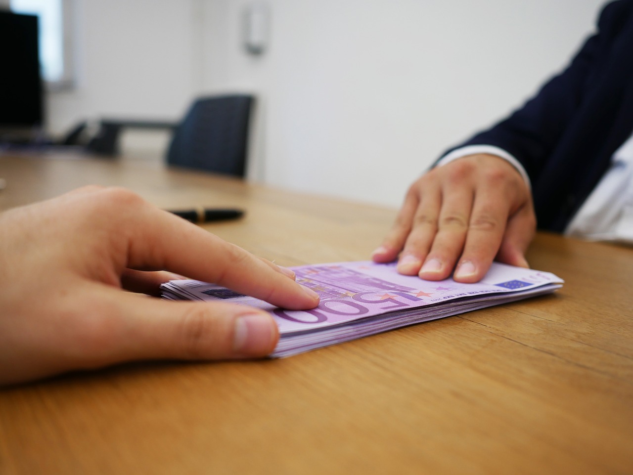 Giocatori di Affari Tuoi sorridono con pacchi e soldi sul tavolo.