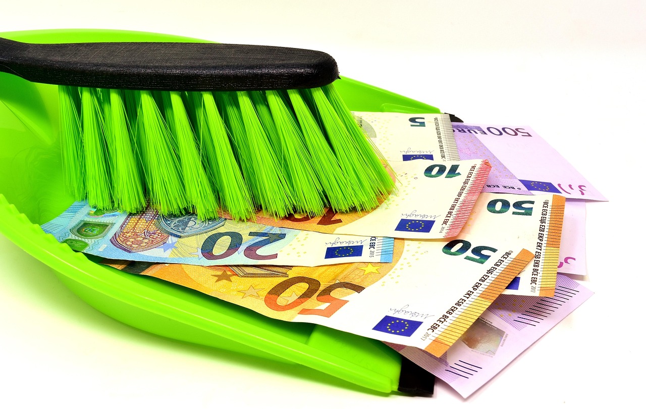 Contanti nascosti sotto un materasso con una mano che li esamina, simbolo di risparmio e evasione fiscale.